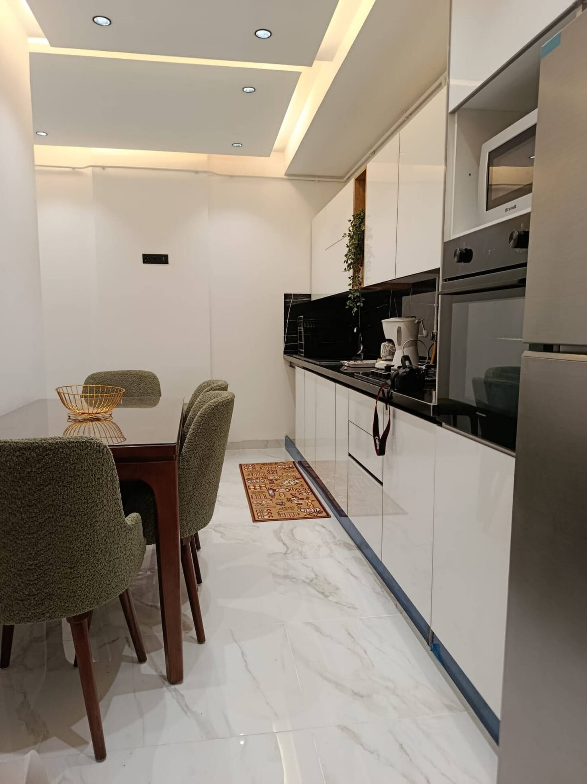 A modern kitchen with white cabinets, a black countertop, and a built-in oven.