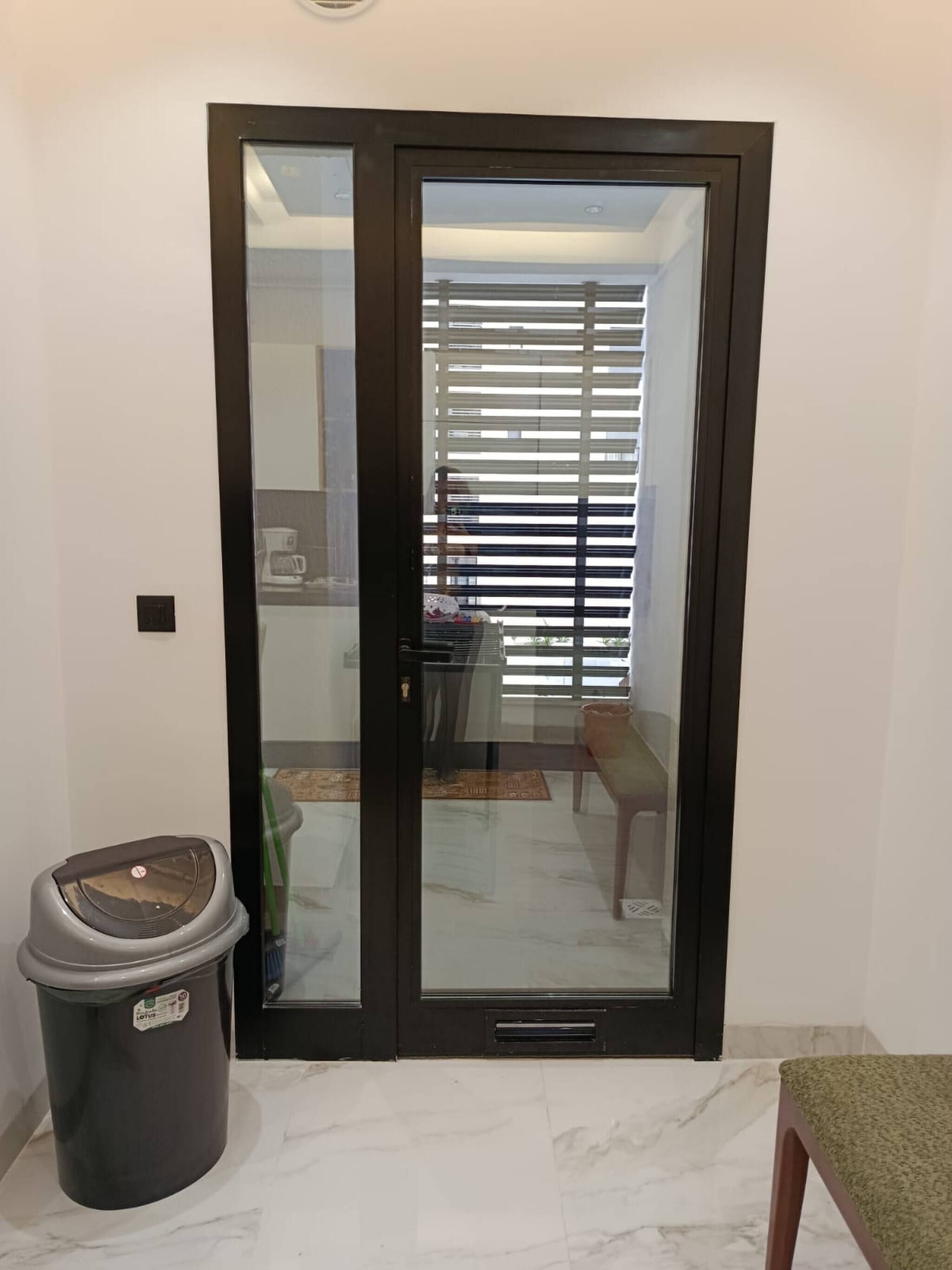 A room with a sliding glass door, a trash bin, and a chair.