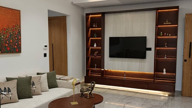 A modern living room with a sofa, coffee table, TV, and built-in shelving. - Charming 2-bedroom Apartment in Tunis With City Views (La Marsa)