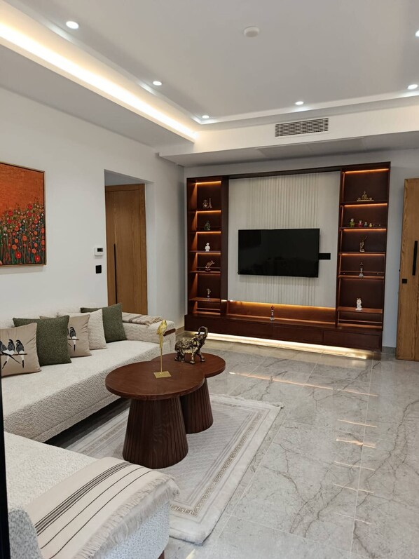 A modern living room with a sofa, coffee table, TV, and built-in shelving. - Charming 2-bedroom Apartment in Tunis With City Views (La Marsa)