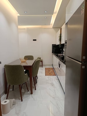 Cocina compacta con refrigerador, estufa y comedor con sillas y una mesa.