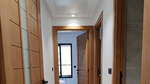 A hallway with wooden doors, a bed, and a window. - Charming 2-bedroom Apartment in Tunis With City Views (La Marsa)