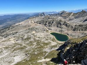 Un paisaje montañoso con un lago cristalino, terreno rocoso y un camino sinuoso.