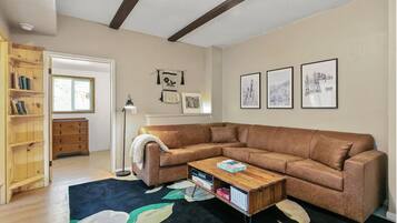 A living room with a sectional sofa, a coffee table, a bookshelf, and framed pictures on the wall.