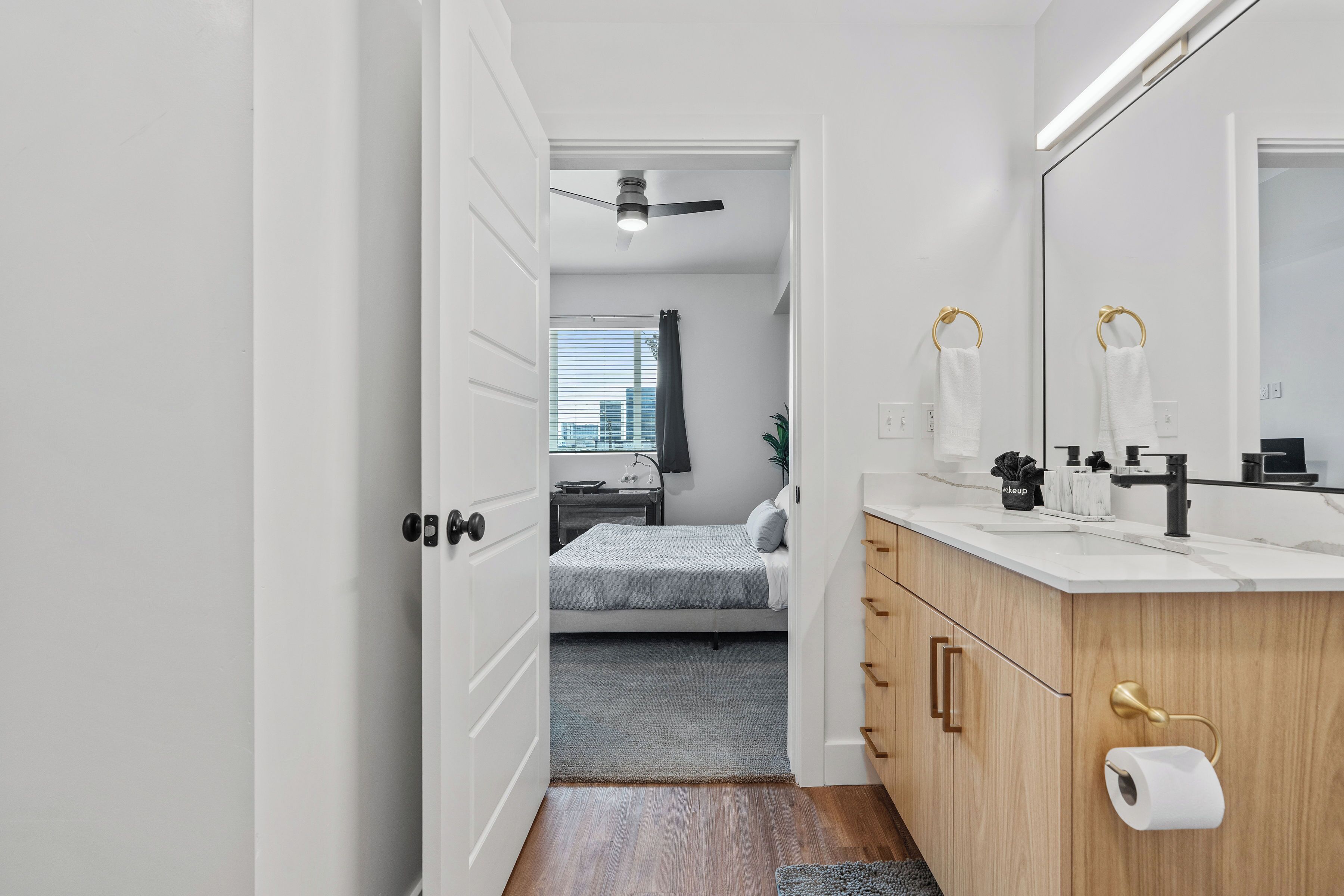 A modern bathroom with a large mirror, a toilet paper holder, and a sink.