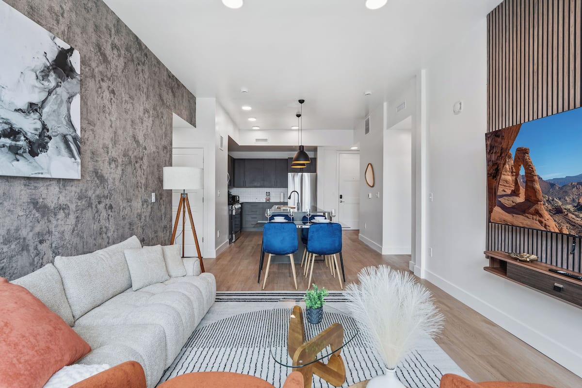 Un salon moderne avec un canapé, une table basse et un coin repas avec des chaises bleues.