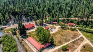 An aerial view of a forested area with several buildings, roads, and a river. - SouthFork Lodge (Lowman)