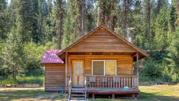 A wooden cabin with a porch, a door with a window, and a small step leading up to the entrance. - SouthFork Lodge (Lowman)
