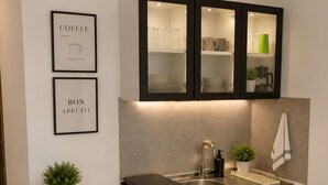 A modern kitchen with a microwave, sink, and cabinets. There are framed pictures on the wall and a small plant on the counter. - Blue Escape Suite (rio hato)