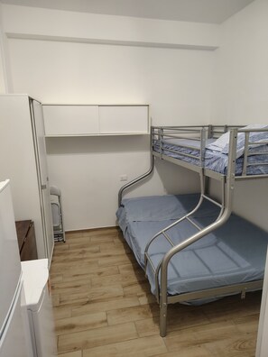 A bunk bed with a desk and chair, a small white cabinet, and a wooden floor. - One-room/mini-apartment in Sperlonga. (Sperlonga)