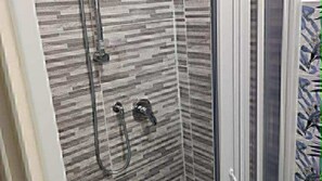 A shower with a patterned tile wall and a glass door. - One-room/mini-apartment in Sperlonga. (Sperlonga)
