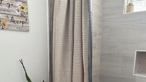 A bathroom with a toilet, a shower curtain, a small plant, and a wall-mounted sign. - Cozy and fully furnished (Savannah)