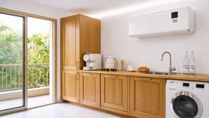 Una cocina moderna con armarios de madera, una cafetera, un lavabo y una lavadora.