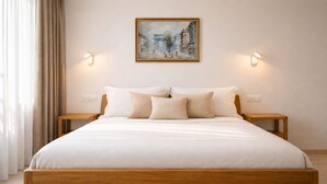 Una habitación de hotel con una cama grande, dos mesitas de noche, un cuadro en la pared y una ventana con cortinas.