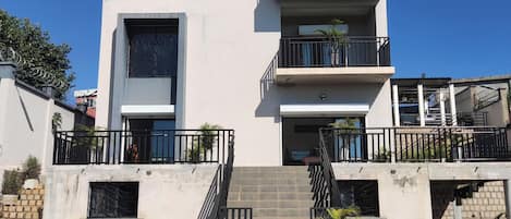 Un immeuble résidentiel à plusieurs étages, doté de balcons, d’un escalier et d’un garage.