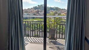Un balcón con vistas a una zona residencial, barandilla metálica y planta en maceta.