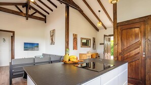 Una cucina con una grande isola, travi in legno e un'area pranzo con un divano.