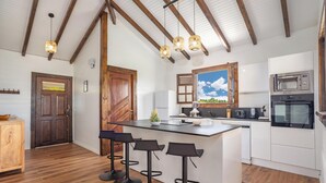 Una cucina con travi in legno, una grande isola con sgabelli da bar, un forno a microonde e un forno.