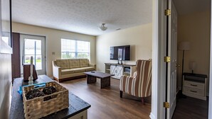 Ein Wohnzimmer mit einer Couch, einem Fernseher, einem Couchtisch und einem gestreiften Sessel.