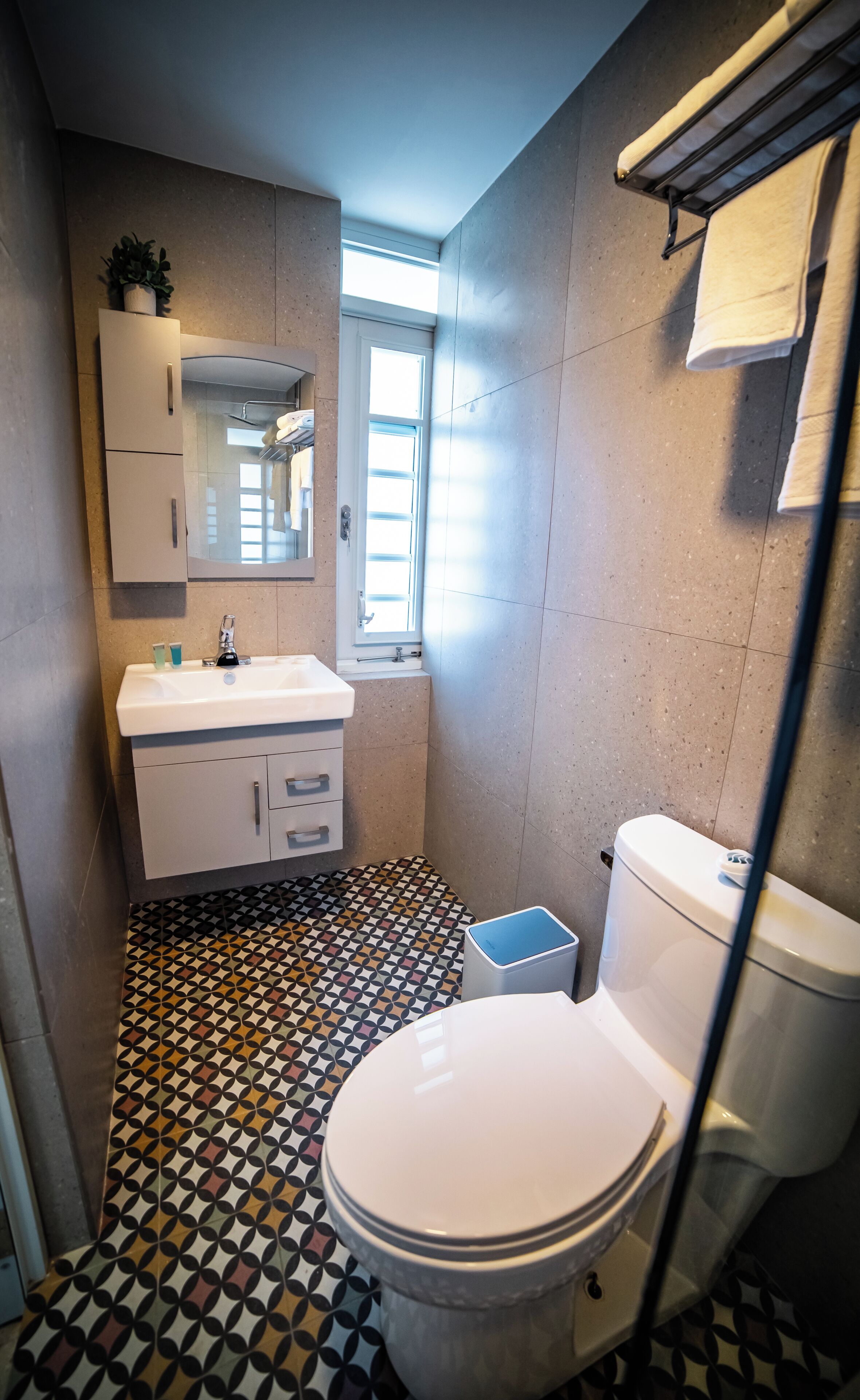 Ein kleines Badezimmer mit einem weißen Waschbecken, einer Toilette und einem fußbodenähnlichen Muster.