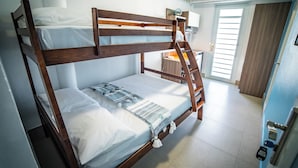 Un letto a castello con una scaletta, un comodino e una finestra con persiane.
