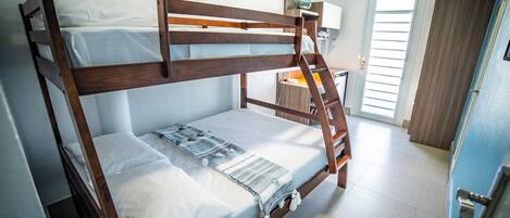 A bunk bed with a ladder, a bedside table, and a window with blinds.