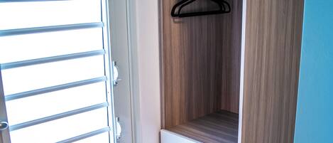 Une pièce avec une armoire en bois, une porte blanche et une fenêtre avec des stores horizontaux.