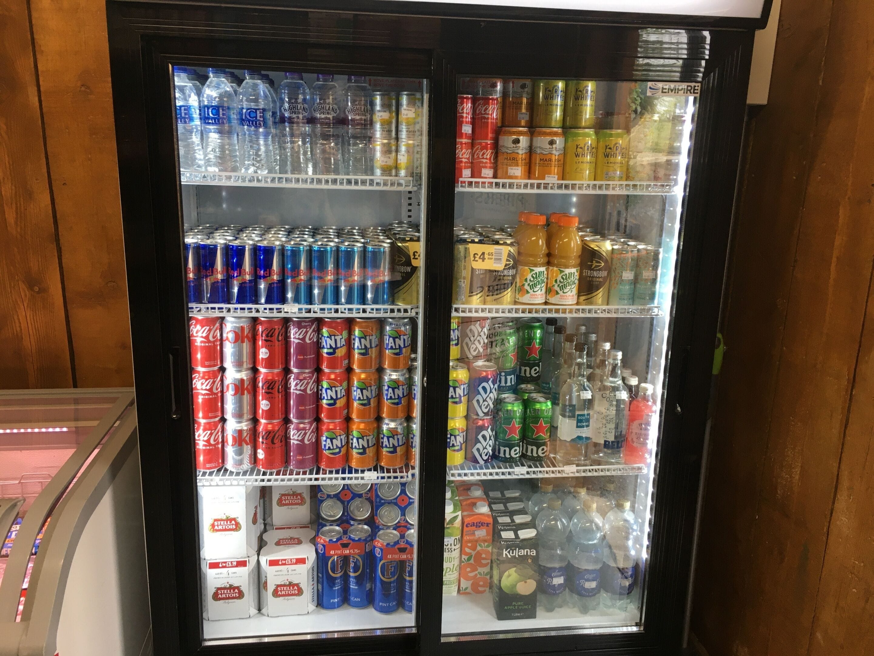 A beverage refrigerator stocked with various drinks including Fanta, Coca-Cola, and other sodas.