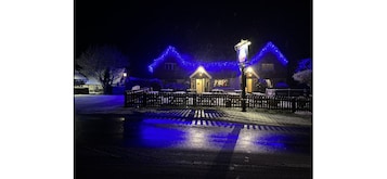Una casa con techo iluminado en azul y valla de madera al frente.