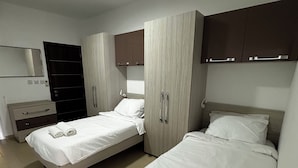 Ett hotellrum med två sängar, en garderob, en spegel och en taklampa.