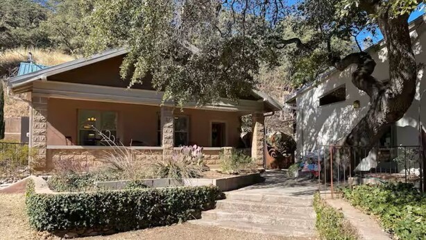 A building with a stone facade, a covered patio, and a gravel pathway leading to the entrance. - Historic Bisbee Retreat - Huge Private Porch -Walk to Town (Bisbee)