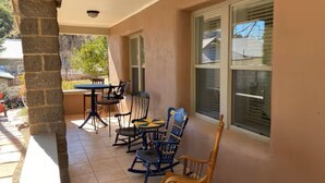 A covered patio with a stone pillar, a table with chairs, and a view of the outside. - Historic Bisbee Retreat - Huge Private Porch -Walk to Town (Bisbee)