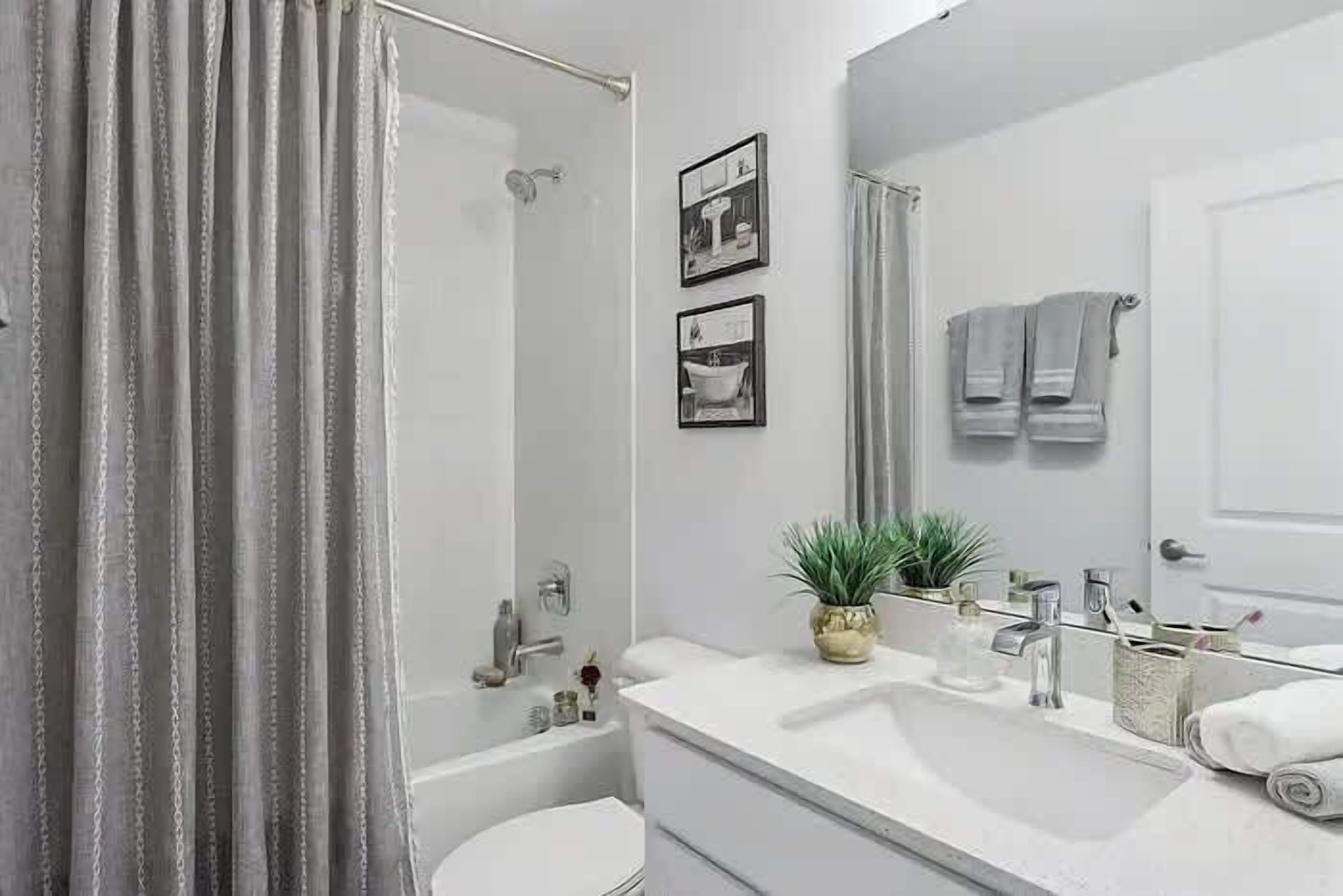 A bathroom with a bathtub, a sink, a mirror, and a shower curtain.