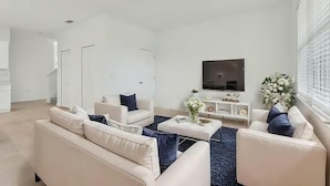 Un salon moderne comprenant un ensemble de canapés, une table basse et un téléviseur fixé au mur.