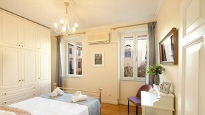 Um quarto com cama, escrivaninha, cadeira e janela com cortinas.