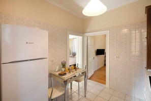 A kitchen with a Bosch refrigerator, a dining table with chairs, and a tiled backsplash. - San Nicolo Dei Veicchi Casa by Corfuescapes (Kerkira)