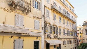 Uma fileira de edifícios amarelos com varandas, persianas e um vaso de planta.