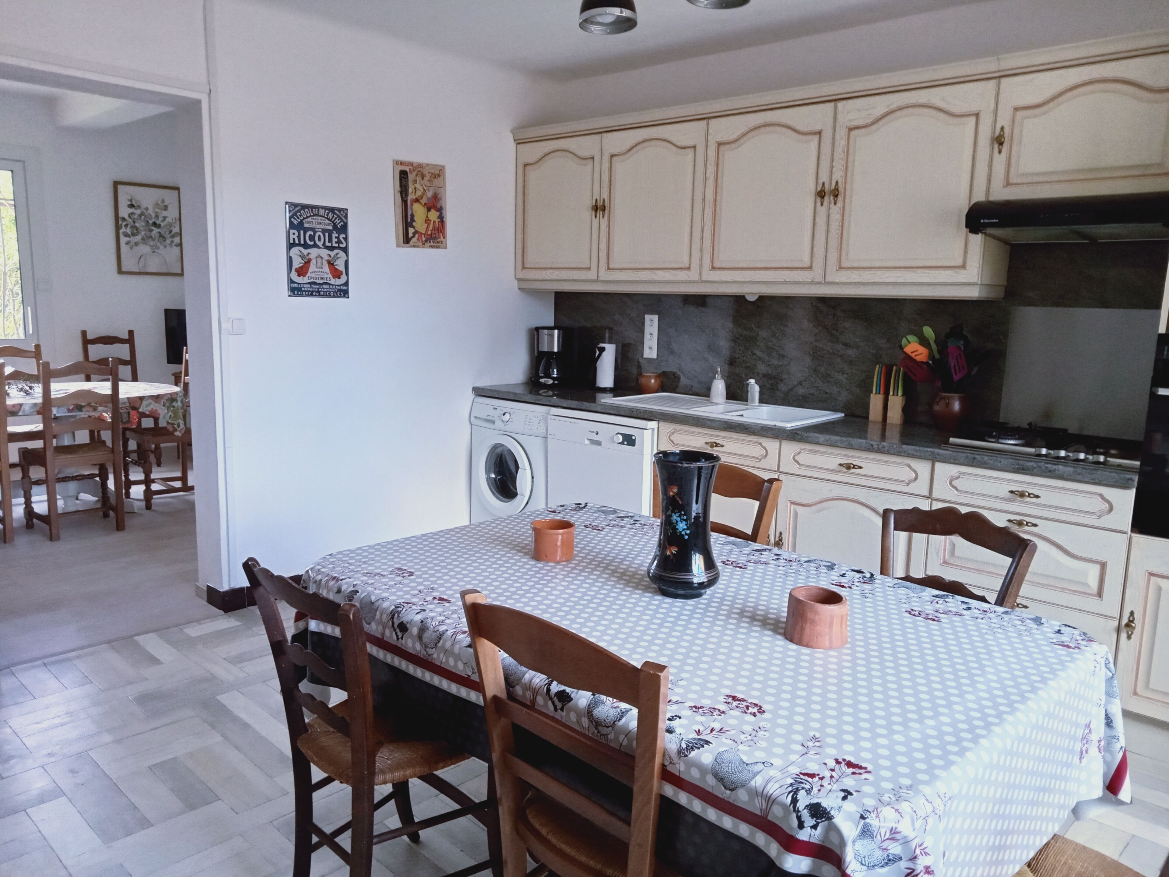 Une cuisine équipée d’un lave-linge, d’une table à manger avec des chaises et d’une machine à café.