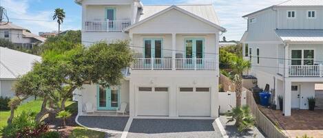 Une maison à deux étages avec un garage, un balcon et un jardin bien entretenu.