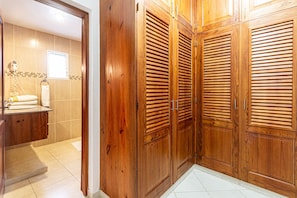 Ein Schrank mit Lamellen, ein Badezimmer mit Toilette und Waschbecken sowie ein Fliesenboden.