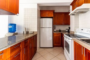 Eine Küche mit Holzausstattung, einem weißen Kühlschrank, einem Herd und einem blauen Wassenspender.