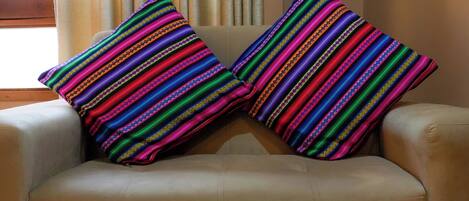 A beige sofa with two colorful striped pillows.