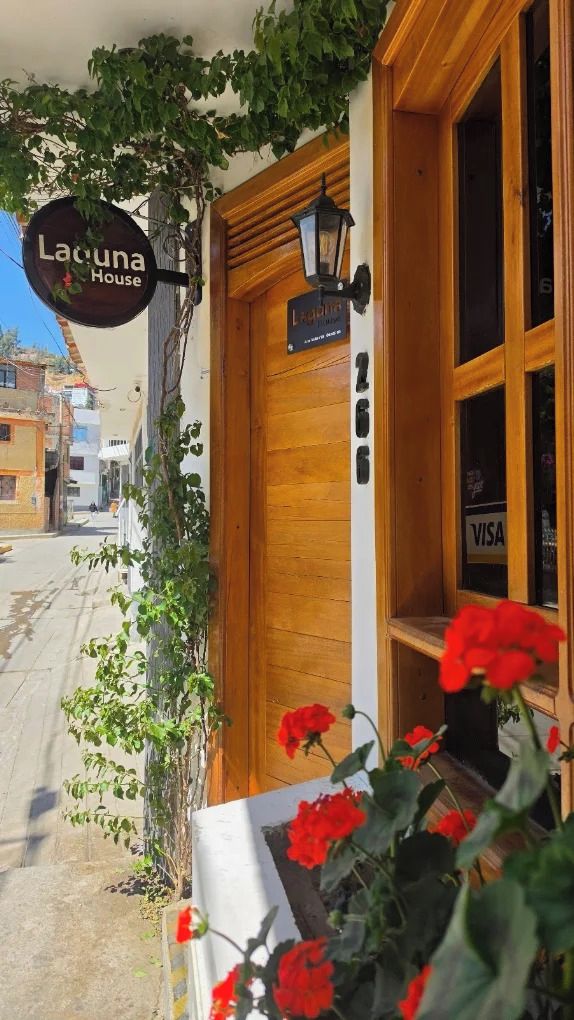 A wooden door with a sign above it, a window with a VISA sign, and a sign for Lacuna House.