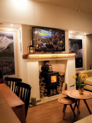 A cozy living room with a fireplace, a television mounted above it, and a dining area with chairs and a table. - LAGUNA HOUSE (Independencia)
