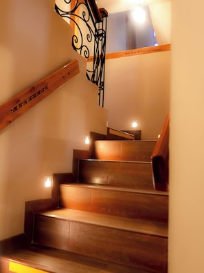 Een houten trap met ijzeren hekwerk en een lamp erboven.