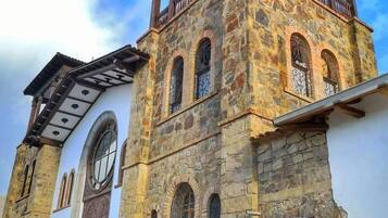 A historic stone building with a bell tower, arched windows, and a balcony.