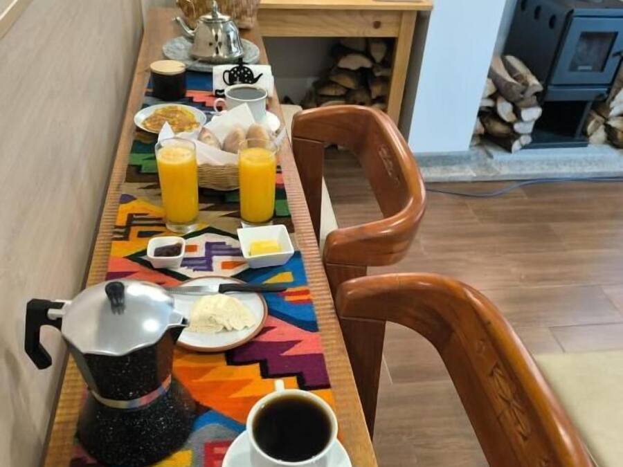 Una mesa de desayuno con café, jugo y alimentos para el desayuno, una cafetera y una silla.