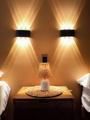 Een nachtkastje met een lamp en twee wandlampen.