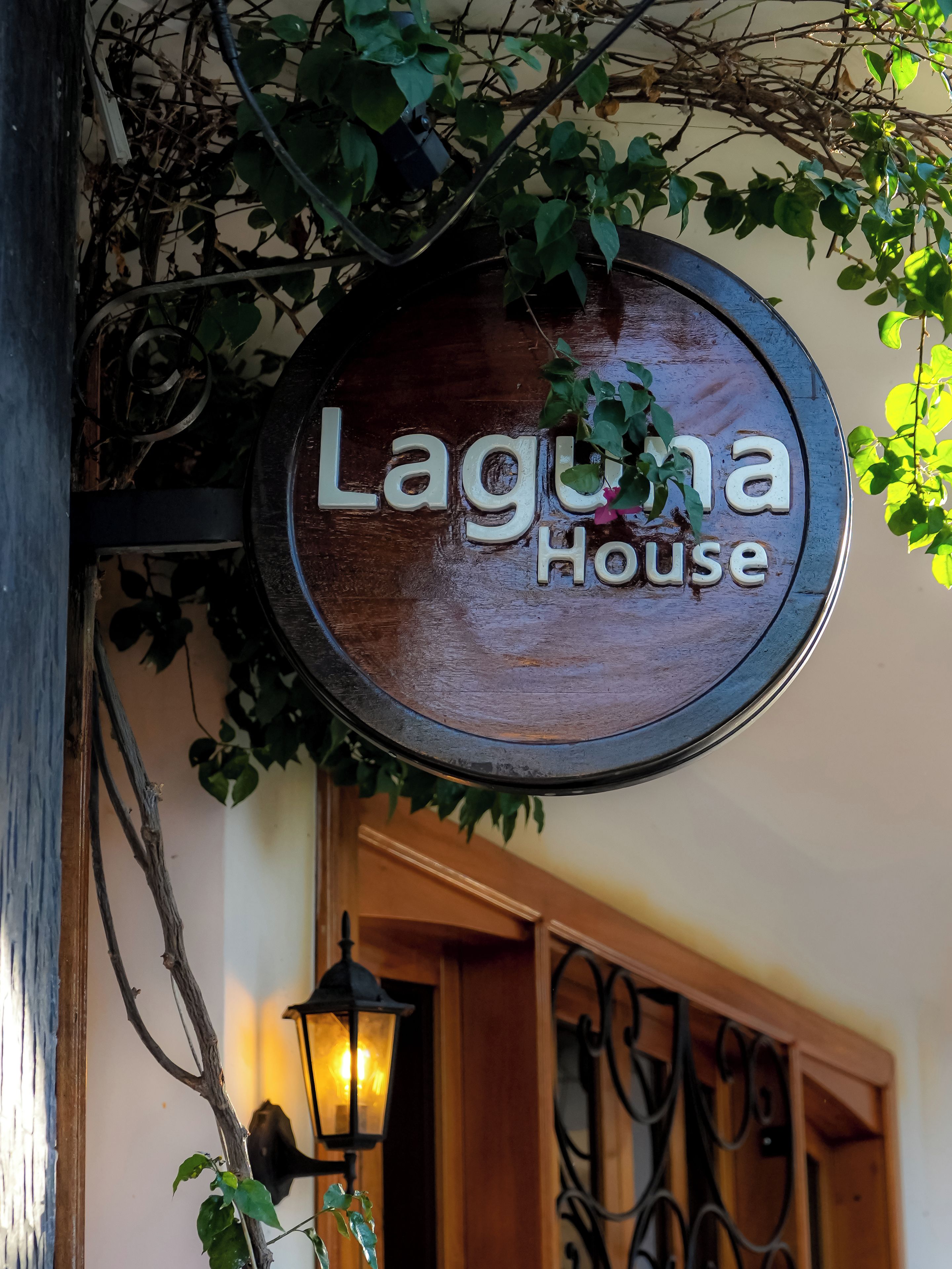 A wooden sign with the text 'Laguna House' hanging above a doorway.