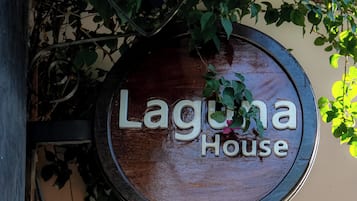 A wooden sign with the text 'Laguna House' hanging above a doorway.